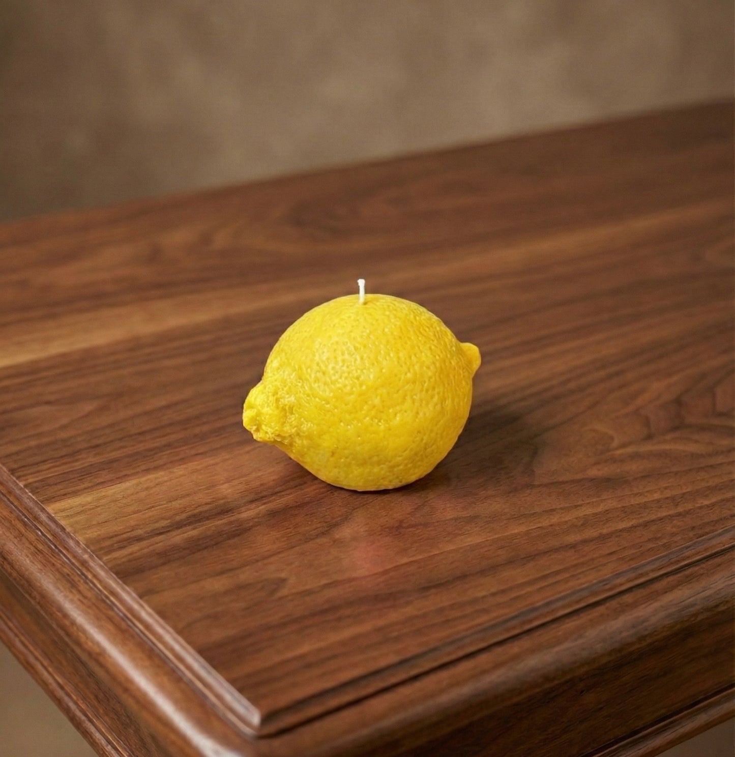 Yellow lemon-shaped candle on a wooden surface