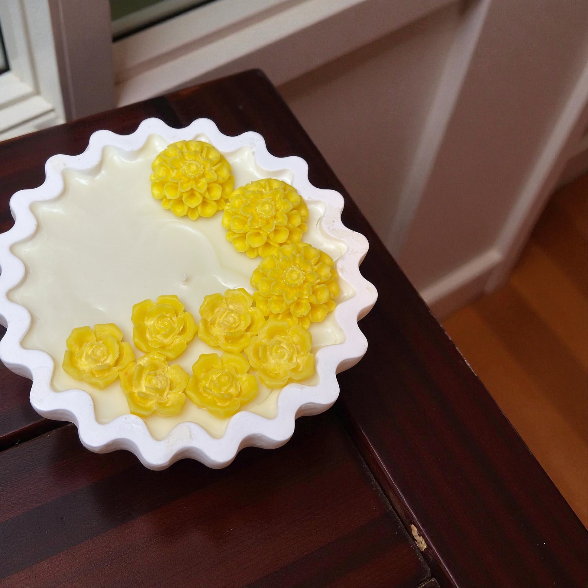 Scalloped edge decorative candle with bright yellow roses and dahlias. Hand-poured soy wax centerpiece in a unique wavy white dish."