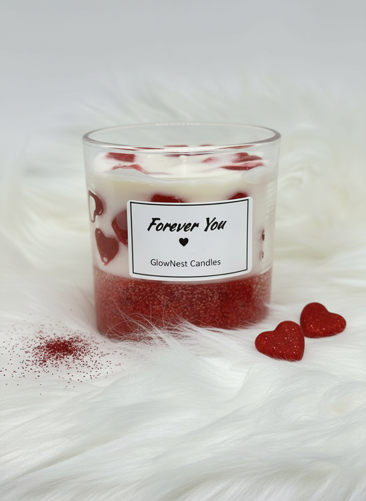 Close-up of GlowNest "Forever You" heart-themed candle featuring a red glitter bottom and wax heart embeds on a white faux fur background with loose red glitter.