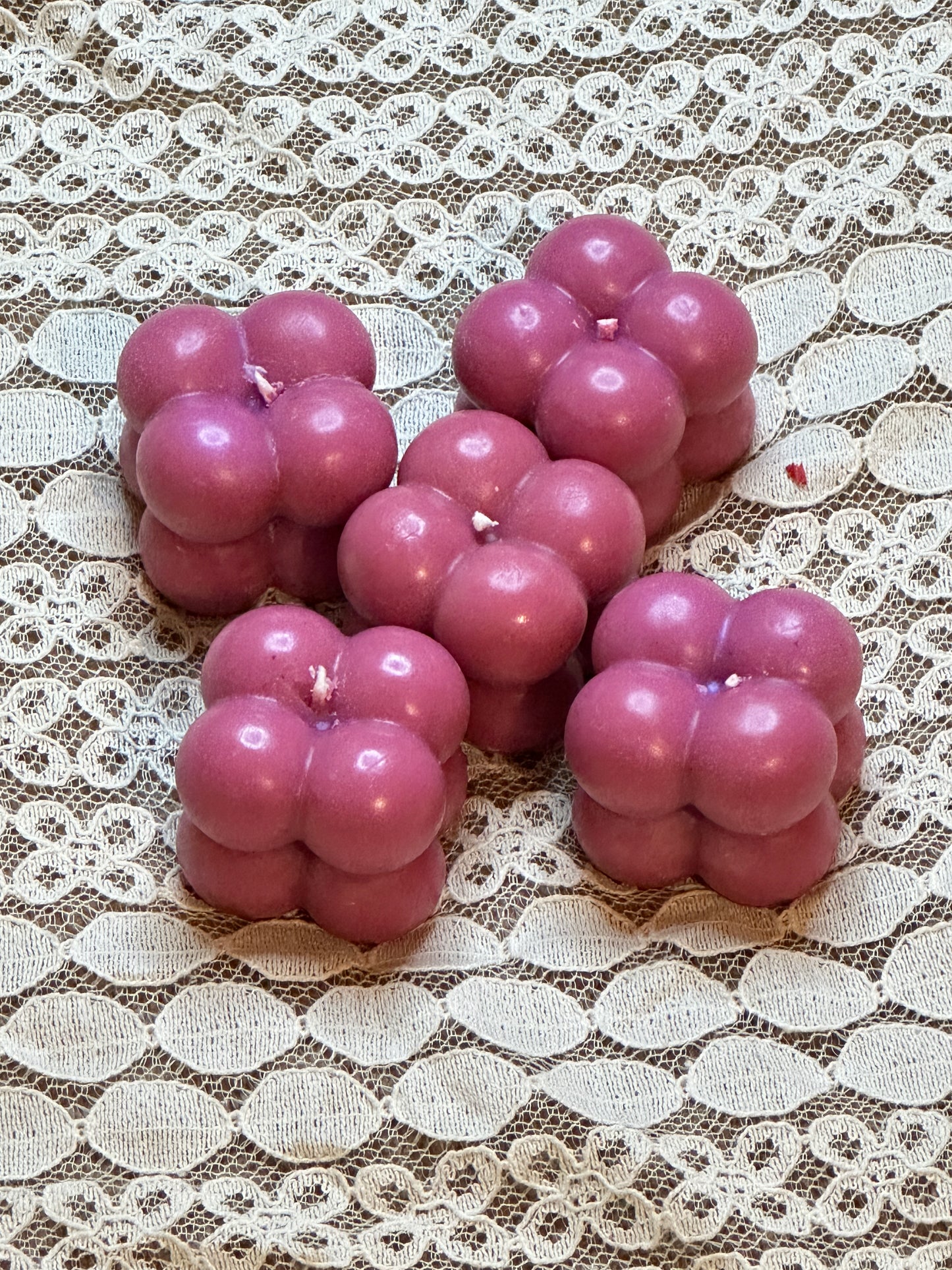 Purple berry-shaped candles on a lace tablecloth