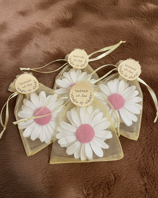 Four handmade daisy-shaped scented candles in white with pink centers, packaged in rustic yellow sheer organza gift bags with 'Handmade with Love' tags. Perfect white wedding return gifts or bridal shower favours.