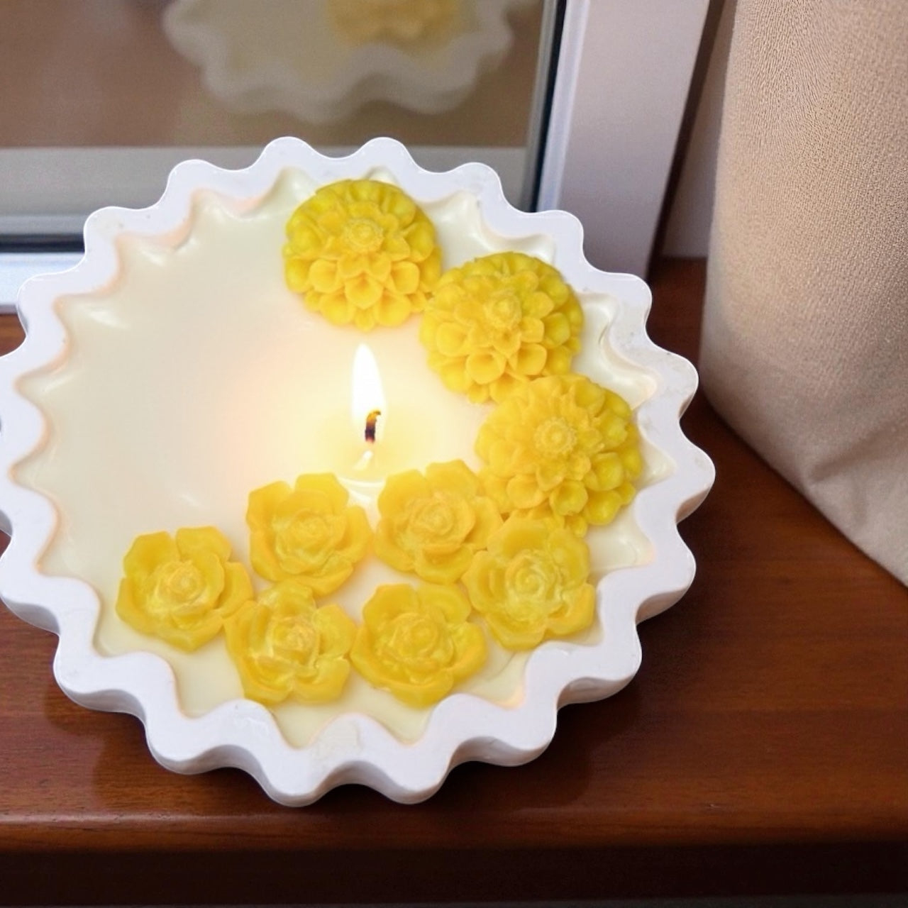 Candle with yellow floral designs on a wooden surface