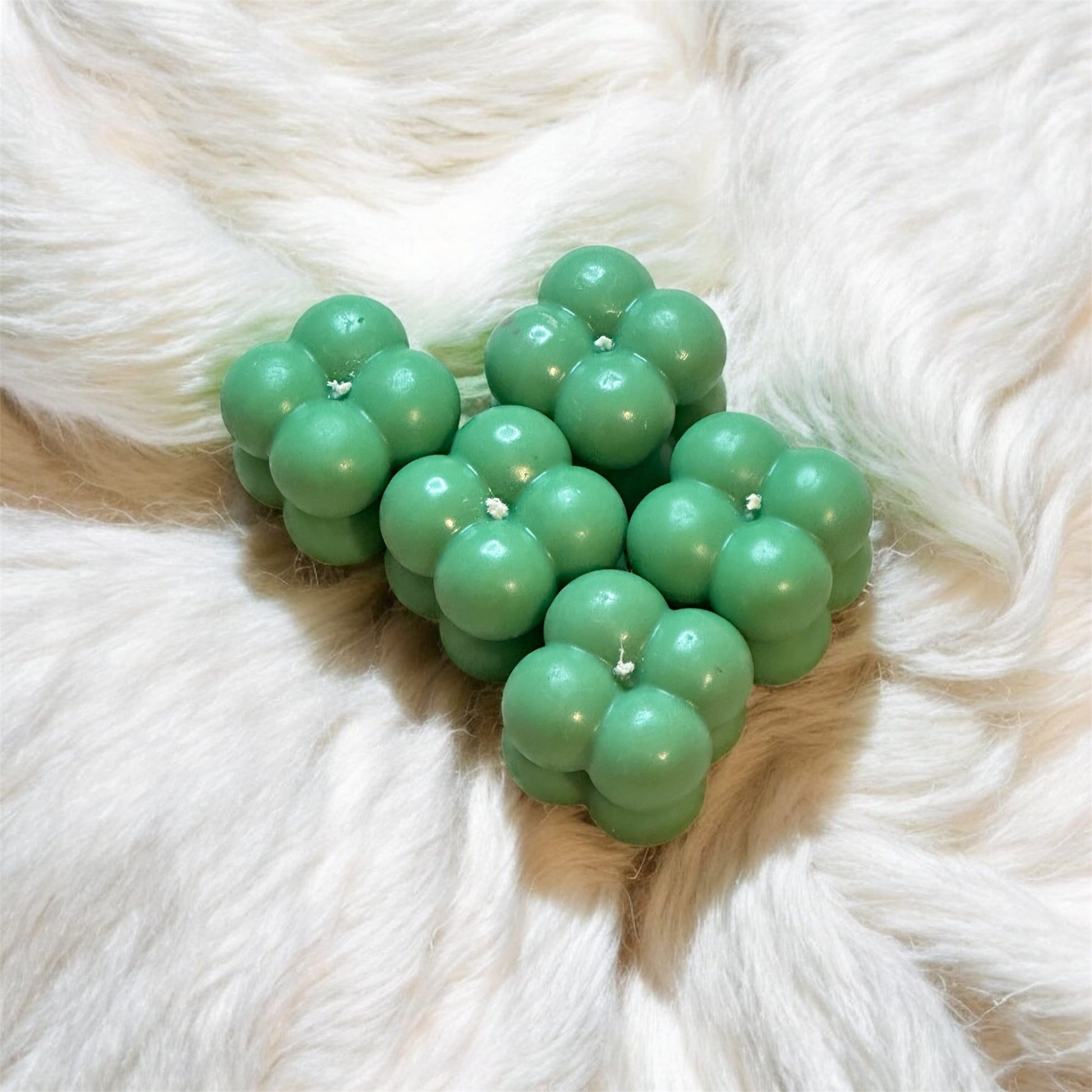 Green bubble gum-shaped candles on a fluffy white surface