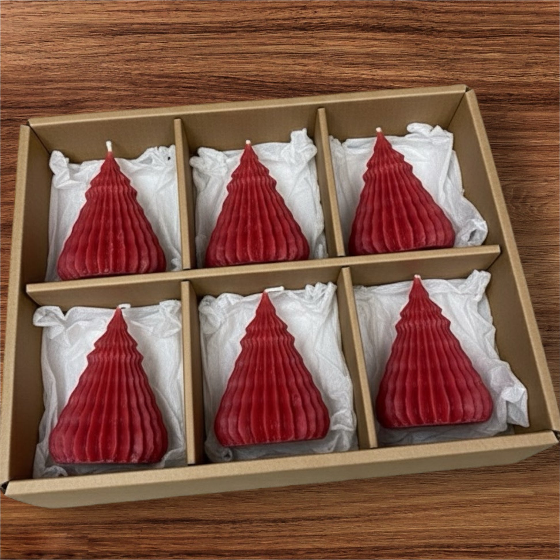 Recycled kraft cardboard gift box presenting a set of six small, deep red, corrugated Christmas tree candles, perfect for holiday decorating or as a festive gift.